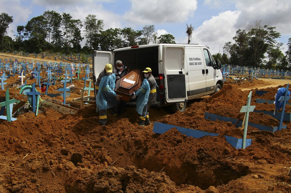 In this Jan. 6, 2021, file photo, cemetery workers carry the remains of 89-year-old Abilio Ribeiro, who died of the coronavirus, to bury at the Nossa Senhora Aparecida cemetery in Manaus, Ama