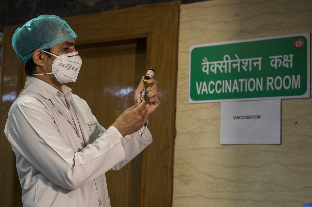 In this Jan. 8, 2021, file photo, a health worker performs a trial run of COVID-19 vaccine delivery system in New Delhi, India. The global death toll from COVID-19 has topped 2 million.