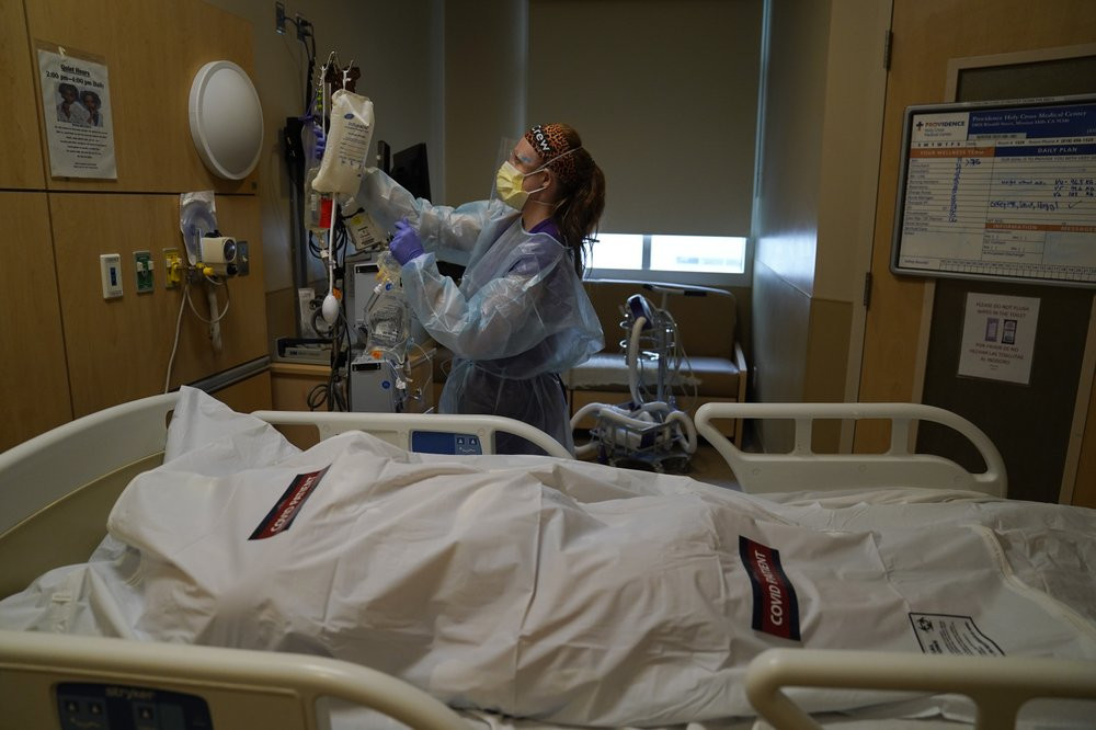 Registered nurse Nikki Hollinger cleans up a room as a body of a COVID-19 victim lies in a body bag labeled with stickers at Providence Holy Cross Medical Center in the Mission Hills section 