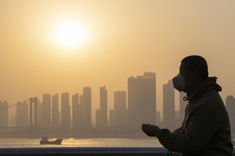 In this Jan. 15, 2021, file photo, a man wearing a mask is silhouetted as the sun sets along the riverbank in Wuhan in central China's Hubei province.
