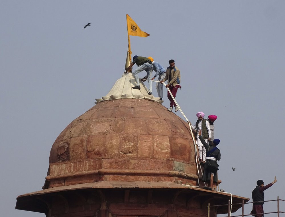 Sikhs hoist a Nishan Sahib, a Sikh religious flag, on a minaret of the historic Red Fort monument in New Delhi, India, Tuesday, Jan. 26, 2021.