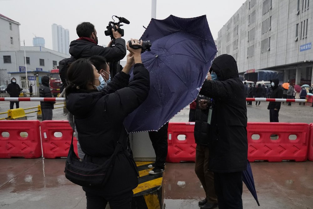 A plainclothes security person uses his umbrella to block journalists from filming after the WHO team arrives at the Baishazhou wholesale market on the third day of field visit in Wuhan in ce