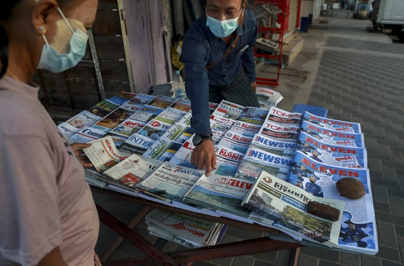A newspaper seller points at a front-page of a newspaper in Yangon, Myanmar, Tuesday, Feb. 2, 2021.