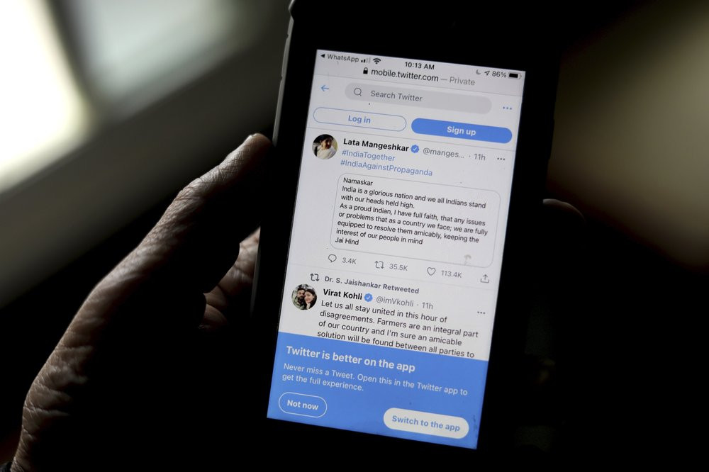 A person reads tweets by Indian celebrities, one of the many backing the Indian government, on his mobile in New Delhi, India, Thursday, Feb. 4, 2021.