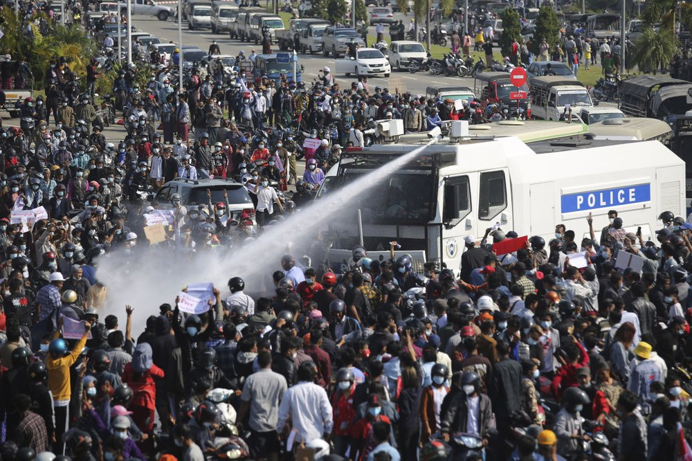 A police truck sprays water to a crowd of protesters in Naypyitaw, Myanmar on Monday, Feb. 8, 2021.