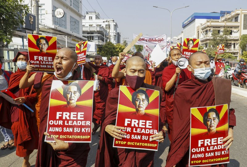 Buddhist monks display pictures of deposed leader Aung San Suu Kyi during a street march against the military coup in Mandalay, Myanmar on Friday, Feb. 12, 2021.
