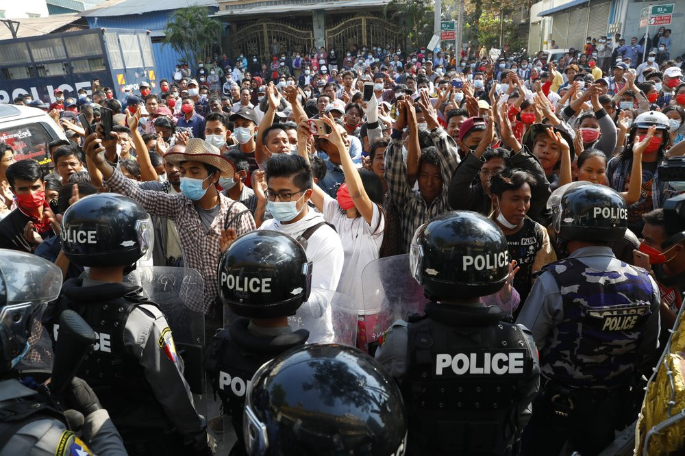 Residents and protesters face riot police as they question them about recent arrests made in Mandalay, Myanmar, Saturday, Feb. 13, 2021.
