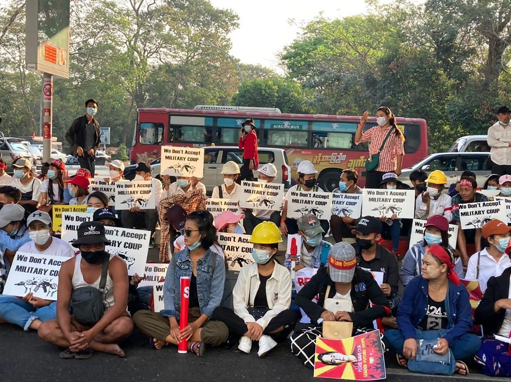 Anti-coup protesters hold signs that read "We Don't Accept Military Coup" as they gather under an elevated roadway outside the Hledan Centre in Yangon, Myanmar Monday, Feb. 22, 2021.