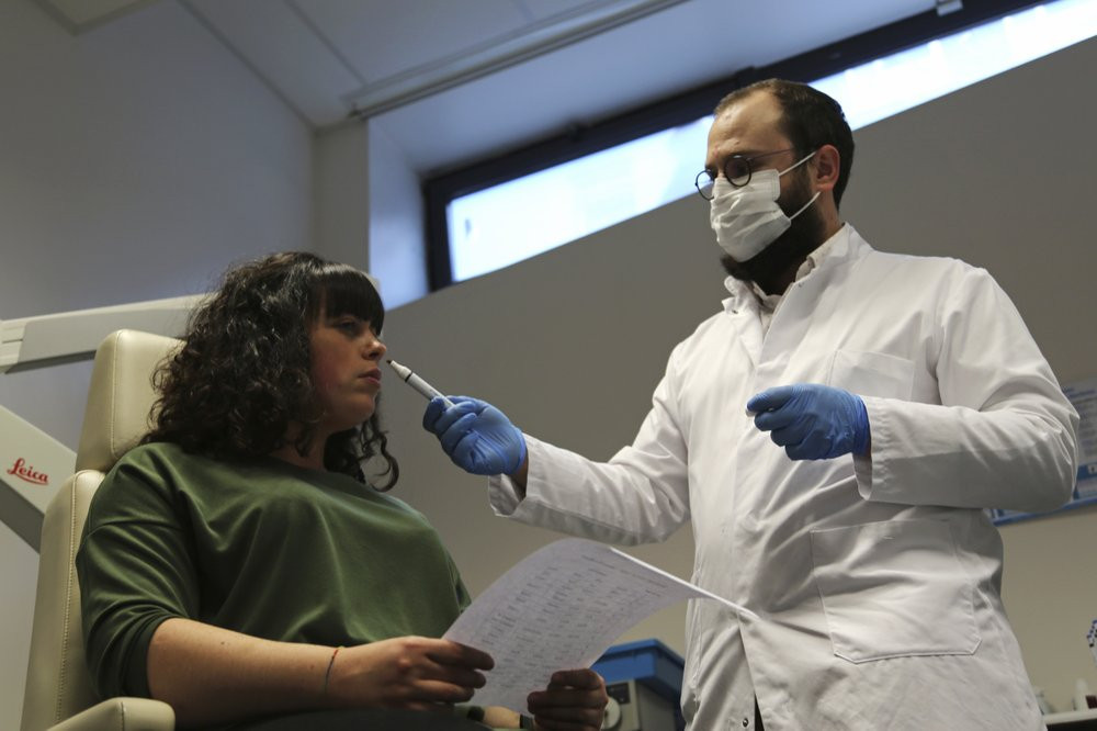 Dr. Clair Vandersteen, right, wafts a tube of odors under the nose of a patient, Gabriella Forgione, during tests in a hospital in Nice, southern France, Monday, Feb. 8, 2021.