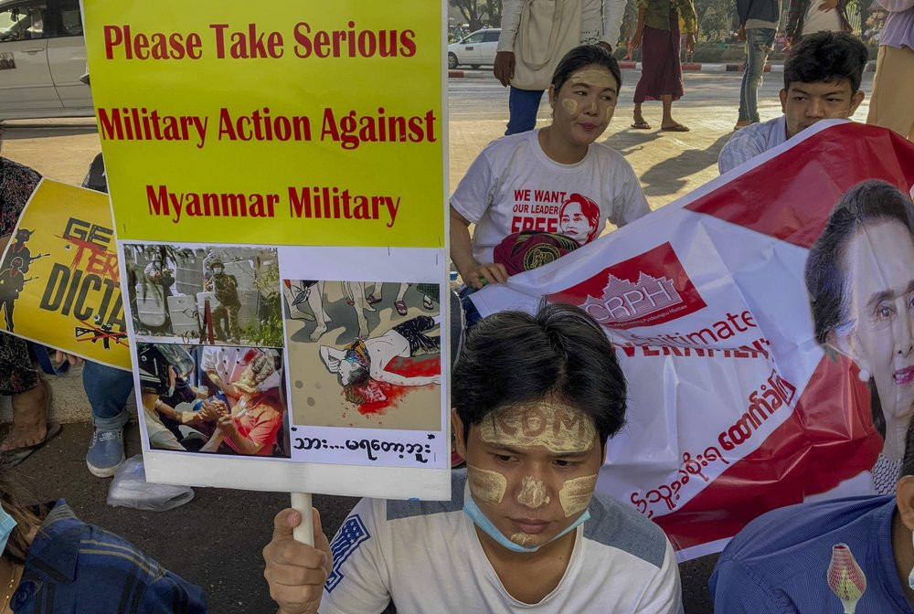 An anti-coup protester holds a placard requesting military action against Myanmar military in Yangon, Myanmar Thursday, Feb. 25, 2021.