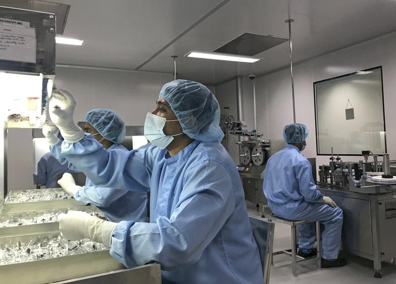 Production personnel perform a visual inspection of filled vaccine vials inside the Incepta plant on the outskirts of Dhaka in Bangladesh Saturday Feb. 13, 2021.