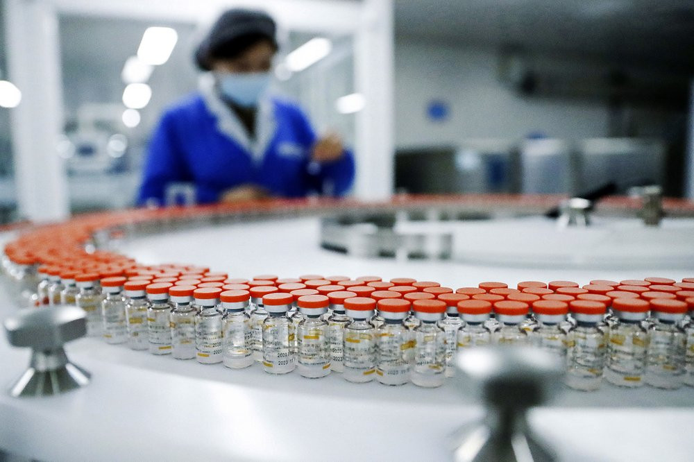 In this Dec. 23, 2020, file photo released by China's Xinhua News Agency, a Sinovac worker checks the labeling on vials of COVID-19 vaccines on a packaging line in Beijing.