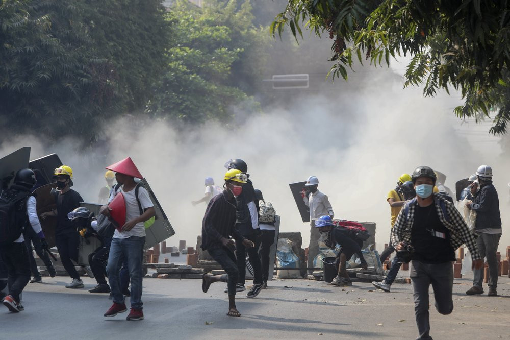 Anti-coup protesters run from teargas and charging riot police and soldiers in Mandalay, Myanmar, Wednesday, March 3, 2021.