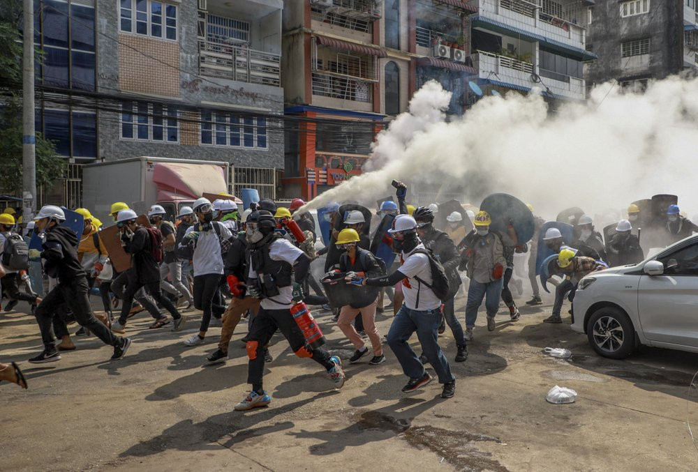 Anti-coup protesters run as one of them discharges a fire extinguisher to counter the impact of tear gas fired by riot policemen in Yangon, Myanmar, Wednesday, March 3, 2021.