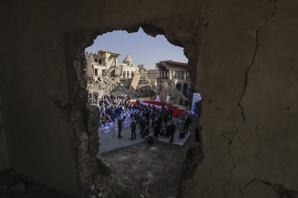 Surrounded by shells of destroyed buildings people arrive to join Pope Francis who will pray for the victims of war at Hosh al-Bieaa Church Square, in Mosul, Iraq, once the de-facto capital o