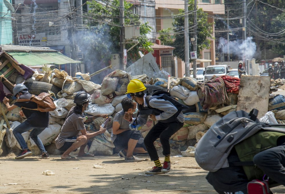 Armed riot policemen charge after firing teargas a rubber bullets as anti-coup protesters abandon their makeshift barricades and run in Yangon, Myanmar Tuesday, March 16, 2021.