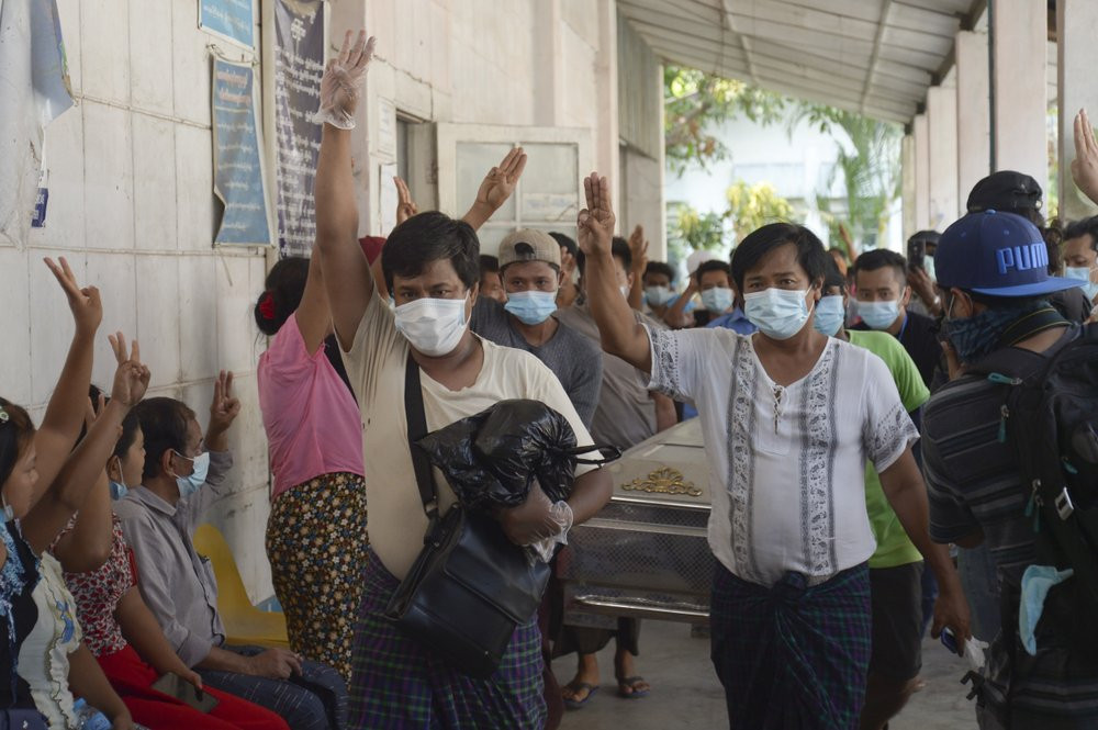 Relatives and friends of Khat Aung Phyo, a boy who was killed by bullet on March 14, raise a three-finger salute, a symbol of resistance, as his body is moved out from a mortuary in Yangon, M