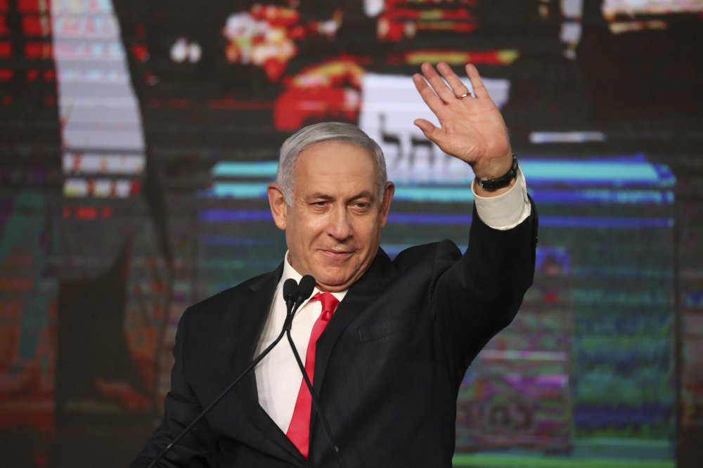 Israeli Prime Minister Benjamin Netanyahu waves to his supporters after the first exit poll results for the Israeli parliamentary elections at his Likud party's headquarters in Jerusalem, Wed