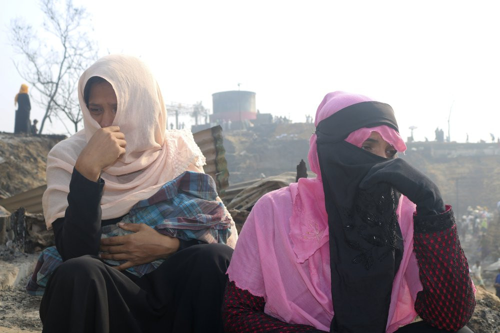 Rohingya refugees cry sitting at the site of Monday's fire at a refugee camp in Balukhali, southern Bangladesh, Tuesday, March 23, 2021.