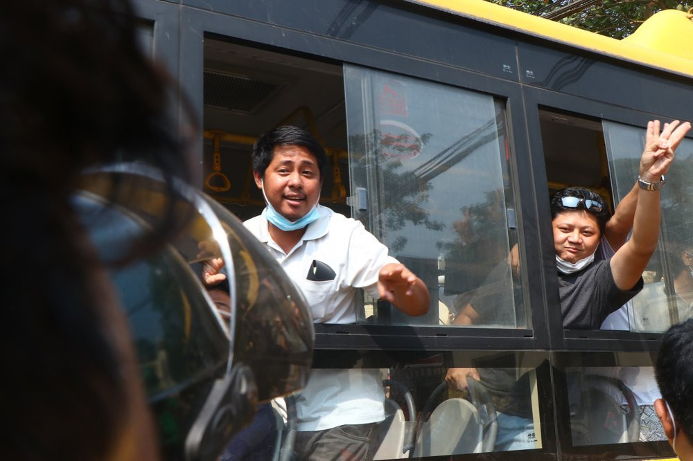 An arrested protester flashes the three-fingered salute while onboard a bus getting out of Insein prison to go to an undisclosed location Wednesday, March 24, 2021 in Yangon, Myanmar.