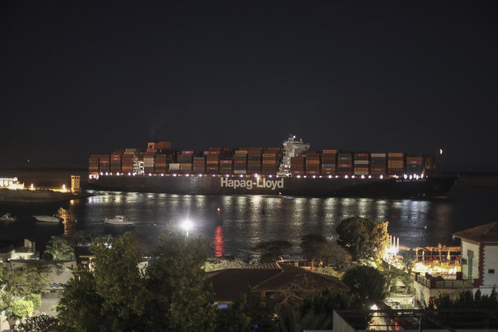 A cargo ship sails through the town of Suez, Egypt, Tuesday, March 30, 2021 as traffic resumed through the Suez canal after it was blocked by a massive ship that had been stuck sideways for n