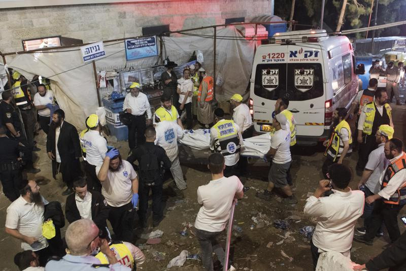 Israeli security officials and rescuers carry a body of a victim who died during a Lag Ba'Omer celebrations at Mt. Meron in northern Israel, Friday, April 30, 2021.