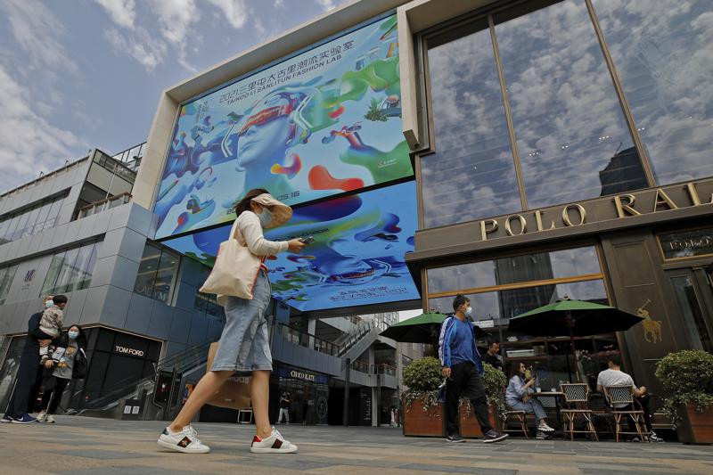 In this May 12, 2021, file photo, shoppers wearing face masks to help curb the spread of the coronavirus walk through the capital popular shopping mall in Beijing.
