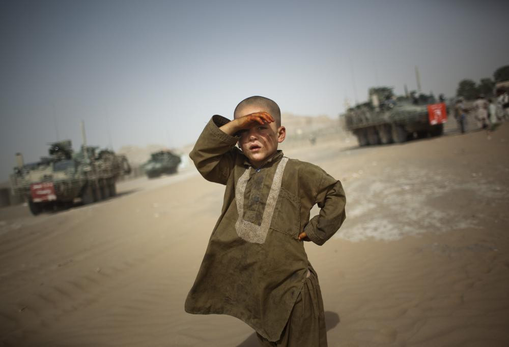 In this Aug. 6, 2009 file photo, a child watches military vehicles of 5th Striker Brigades drive past his village on the outskirts of Spin Boldak, about 100 kilometers (63 miles) southeast of