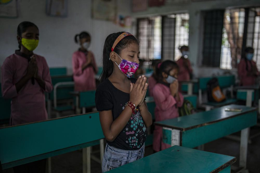 School children attend morning assembly inside a classroom on the first day of partial reopening of schools in Noida, a suburb of New Delhi, India, Wednesday, Sept. 1, 2021.