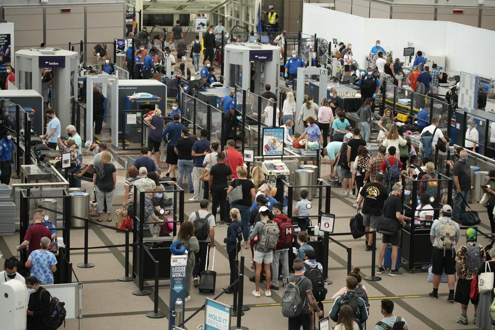 Travelers wear face coverings in the line for the north security checkpoint in the main terminal of Denver International Airport Tuesday, Aug. 24, 2021, in Denver.