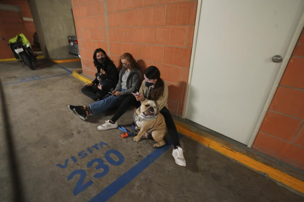 People gather outside thier building with their pet after a strong earthquake, in Mexico City, Tuesday, Sept. 7, 2021.