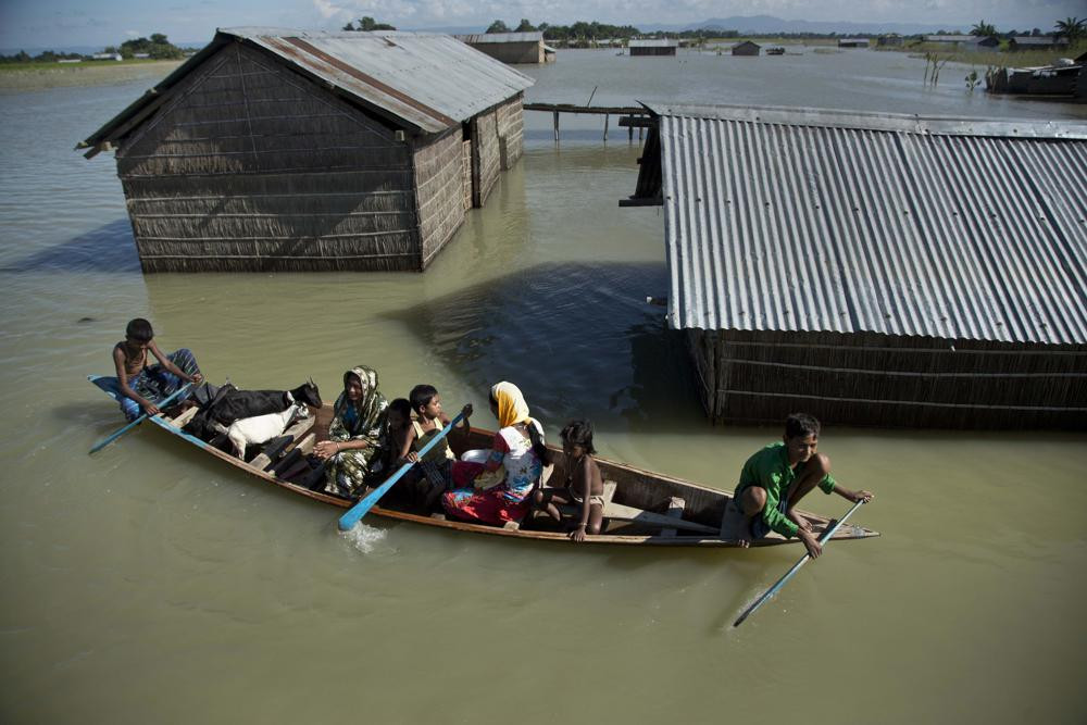 In this July 31, 2016, file photo, a flood-affected family with their goats travel on a boat in the Morigaon district, east of Gauhati, northeastern Assam state, India.