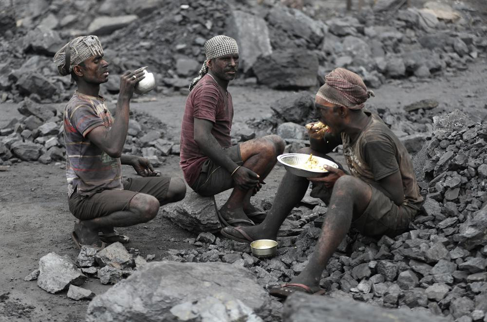 In this Oct. 23, 2019, file photo, laborers eat lunch at a coal loading site in the village of Godhar in Jharia, a remote corner of eastern Jharkhand state, India.