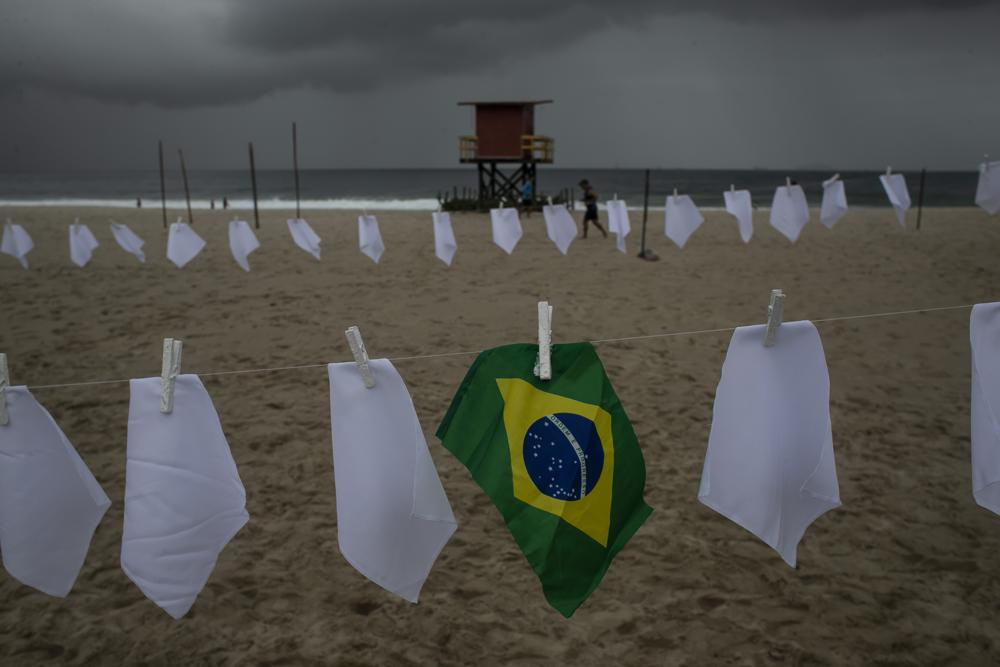 A Brazilian flag hangs on a clothesline on Copacabana beach amid white scarves that represent those who have died of COVID-19 in Rio de Janeiro, Brazil, Friday, Oct. 8, 2021.