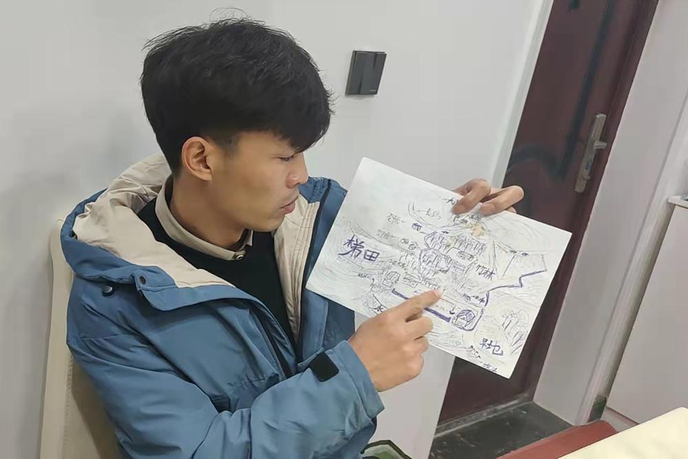 Li Jingwei points to a detail a map he drew from memory of his childhood village as he sits in Lankao in central China's Henan Province, Wednesday, Jan. 5, 2022.