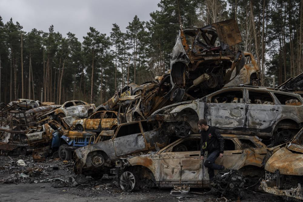 A man walks next a storage place for burned vehicles in Irpin, on the outskirts of Kyiv, Thursday, April 21, 2022.