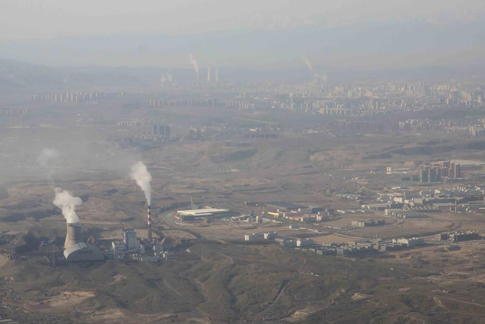 FILE - Smoke and steam rise from towers at the coal-fired Urumqi Thermal Power Plant as seen from a plane in Urumqi in western China's Xinjiang Uyghur Autonomous Region on April 21, 2021.