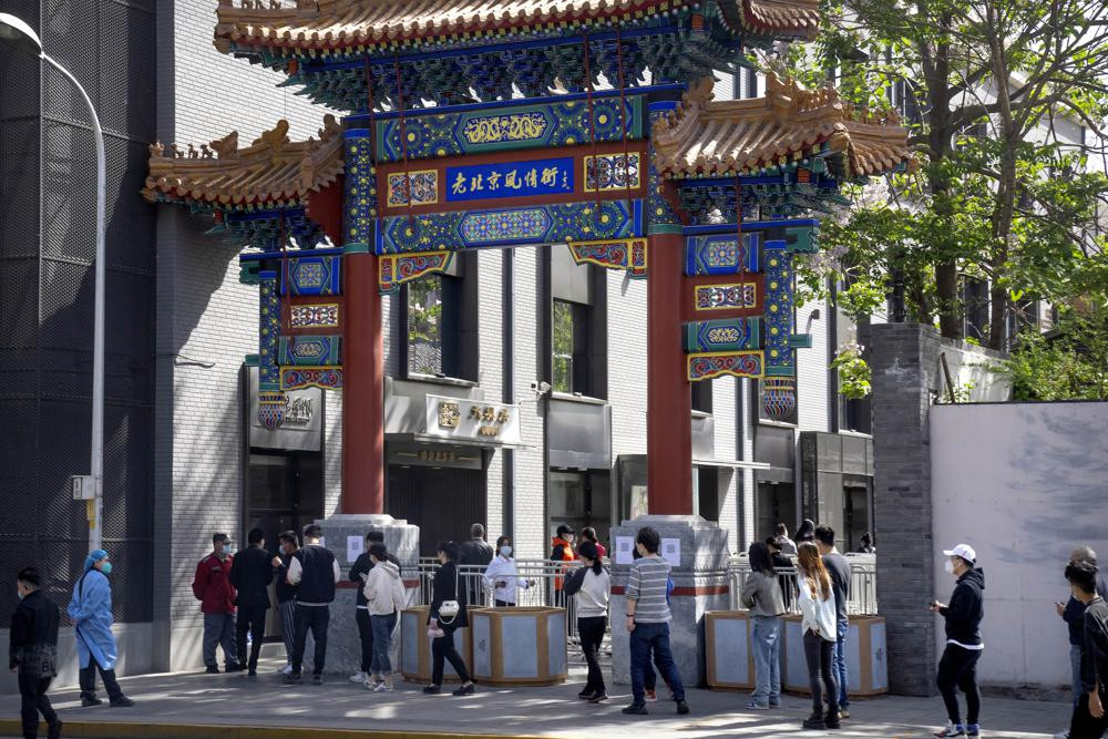 People wearing face masks line up for coronavirus tests in a neighborhood in the Dongcheng district of Beijing, Tuesday, April 26, 2022.