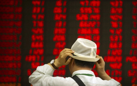 In this Sept. 5, 2019, file photo, an investor adjusts his hat as he monitors stock prices at a brokerage house in Beijing.