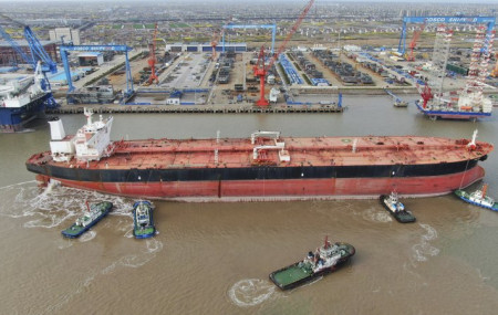 In this photo taken Monday, March 16, 2020, tugboats push a 300,000-ton very large crude carrier (VLCC) to a shipyard on the Yangtze River for retrofit in Qidong city in east China's Jiangsu 
