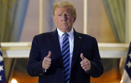 US President Donald Trump stands on the balcony outside of the Blue Room as returns to the White House Monday, Oct. 5, 2020, in Washington, after leaving Walter Reed National Military Medical