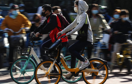 People wearing face masks to help curb the spread of the coronavirus ride bicycle during the morning rush hour in Beijing, Monday, Oct. 12, 2020.