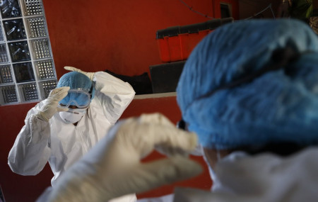 Doctors Delia Caudillo, left, and Monserrat Castaneda, put on protective gear as they prepare to conduct a COVID-19 test at a home in the Venustiano Carranza borough of Mexico City, Thursday,