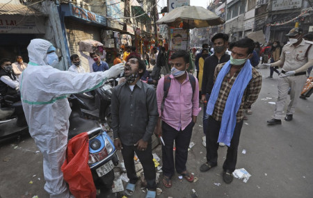 A health worker takes a sample to test for COVID-19 test at a market place in New Delhi, India, Thursday, Nov. 19, 2020.