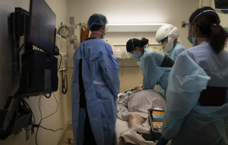 In this Nov. 19, 2020, file photo, EMT Giselle Dorgalli, third from right, performs chest compression on a patient who tested positive for coronavirus in the emergency room at Providence Holy