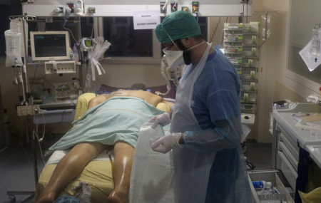 Paramedic Bertrand Brissaud, cares for the patient in room No. 10, a few hours before he died after his nearly month-long battle against COVID-19 at Bichat Hospital, AP-HP, in Paris Tuesday, 