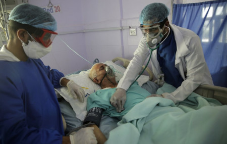 In this June 14, 2020, file photo, medical workers attend to a COVID-19 patient in an intensive care unit at a hospital in Sanaa, Yemen.