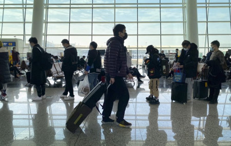 Passengers wearing face masks to protect against the spread of the coronavirus line up at a boarding gate at Wuhan Tianhe International Airport in Wuhan in central China's Hubei Province, Thu