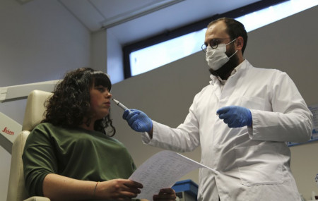 Dr. Clair Vandersteen, right, wafts a tube of odors under the nose of a patient, Gabriella Forgione, during tests in a hospital in Nice, southern France, Monday, Feb. 8, 2021.