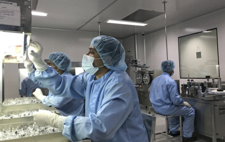 Production personnel perform a visual inspection of filled vaccine vials inside the Incepta plant on the outskirts of Dhaka in Bangladesh Saturday Feb. 13, 2021.